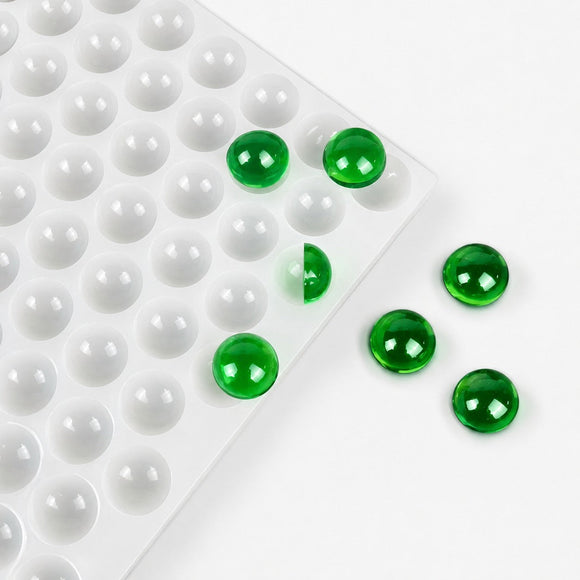 Fertige smaragdgrüne Fruchtgummimuster neben einer gewerblichen Silikonform bei der Nachbearbeitung