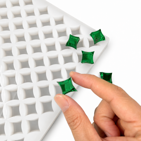 Hand drückt einen fertigen smaragdgrünen sternförmigen Fruchtgummi in einer flexiblen Silikonform