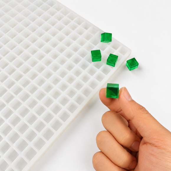 Close-up of an emerald green 1mL cube gummy beside a 736-cavity mold